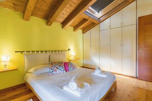 A bedroom with a bed, bedside lamps, a wardrobe, and a skylight.