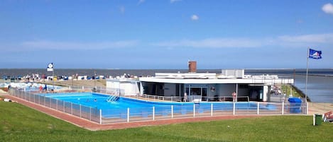 A swimming pool area with a building that has a sign reading "Schwimmbad".