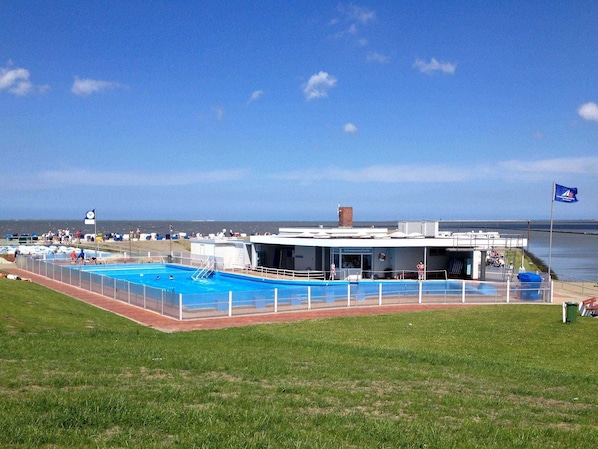 A swimming pool area with a building that has a sign reading "Schwimmbad".