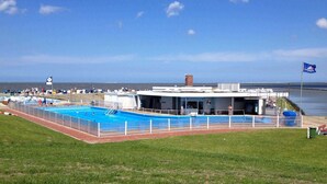 A swimming pool area with a building that has a sign reading "Schwimmbad". - Apartment East with balcony - Trabbi house (Wittmund)