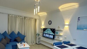 Een moderne woonkamer met een bank, salontafel, televisie en een eethoek met stoelen en een tafel.