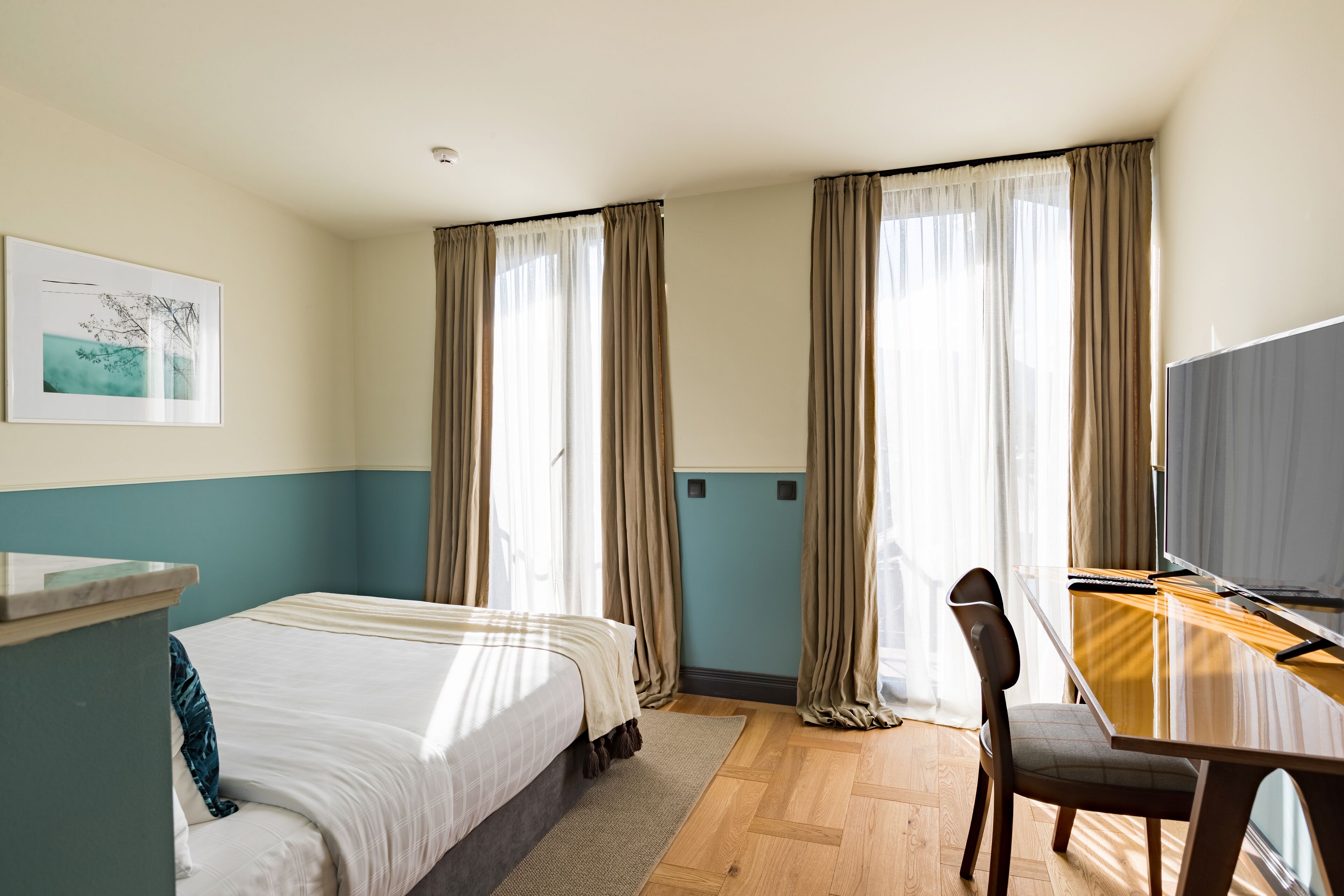 A hotel room with a bed, a desk, a chair, and a television.
