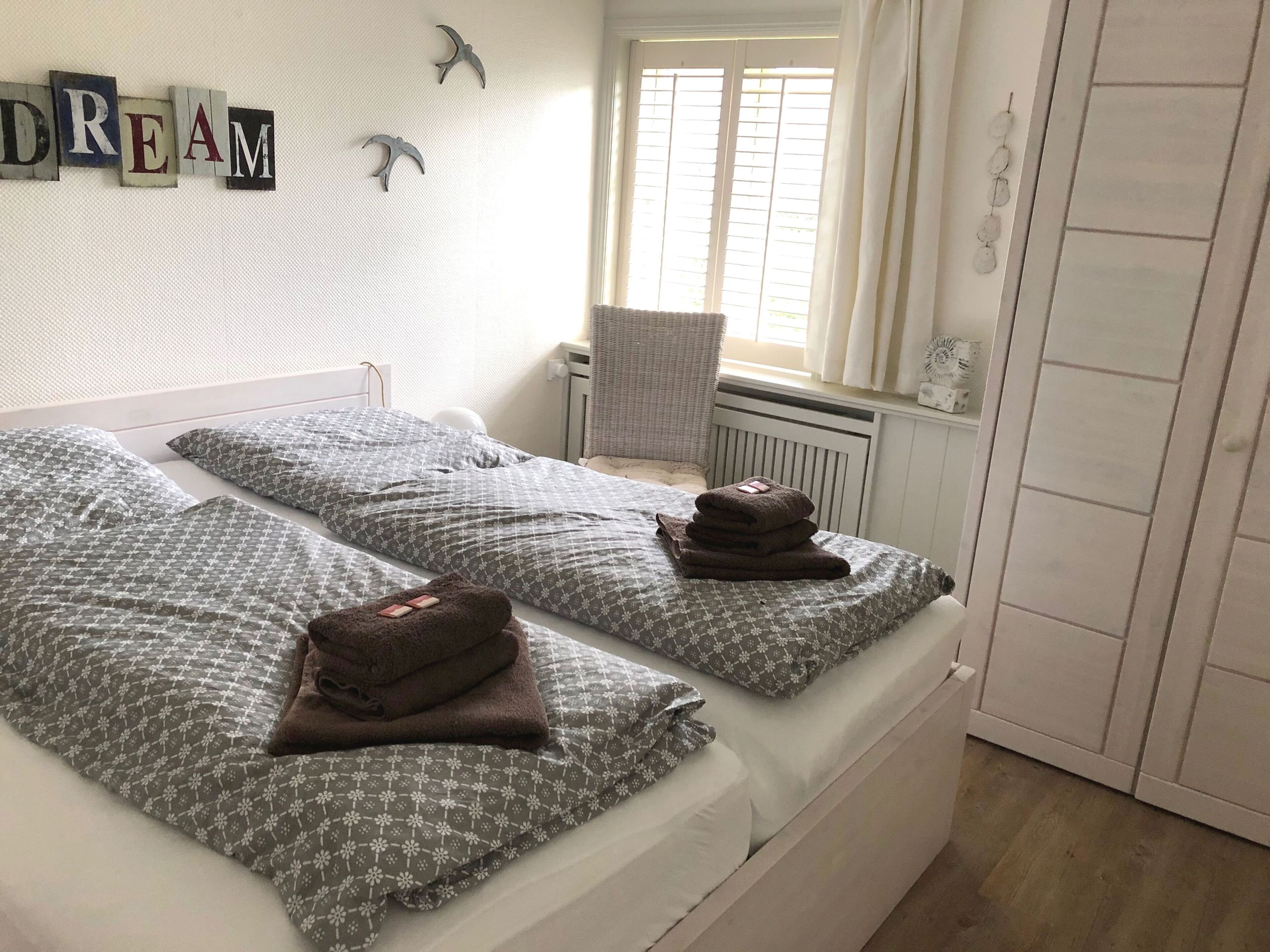 A double bed with patterned bedding, a chair, and a radiator.