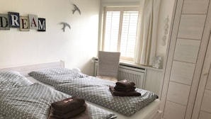 A double bed with patterned bedding, a chair, and a radiator.