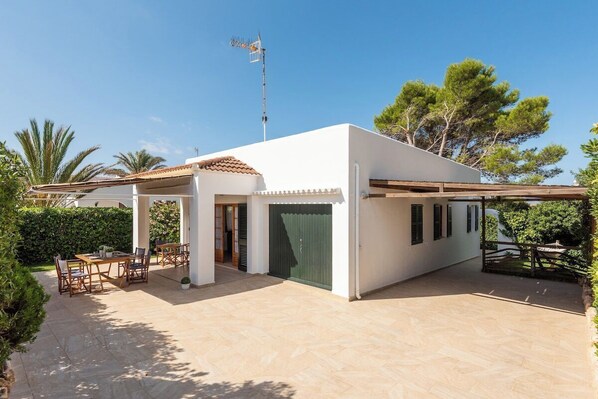 Una casa moderna con un patio, mobiliario exterior y una puerta verde.