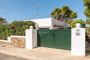 A gated entrance with a green door, a stone wall, and a sign with the number 86.