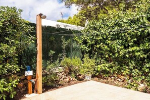Un jardín con un poste de madera, una pared de piedra y un área pavimentada.