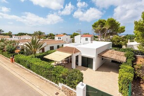 Ein modernes Haus mit Terrasse, umgeben von Grün und freiem Blick aufs Meer.