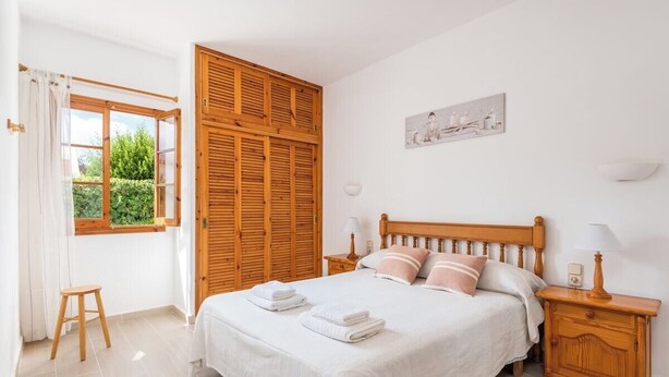 Ein Schlafzimmer mit Bett, Holzschrank und einem Fenster mit Vorhängen.