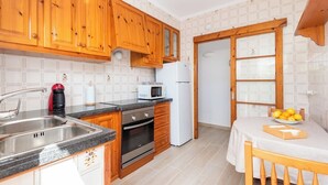 Eine Küche mit Holzschränken, einer Edelstahl-Spüle, einer Mikrowelle und einem Kühlschrank.