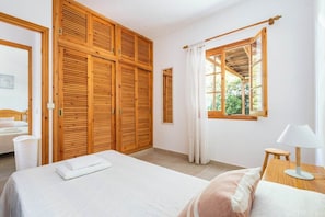 Ein Schlafzimmer mit Bett, Holzschrank und einem fenster mit Vorhängen.