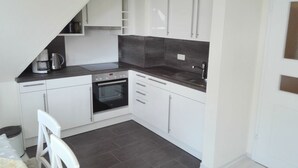 A compact kitchen with white cabinets, a built-in oven, and a dark countertop. - Große Str. 2 Möwe, apt. 29 (Wyk auf Föhr)