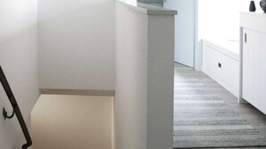Ein modernes Interieur mit einer Treppe, einem Flur und Blick in einen Raum mit einem Fenster.