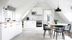 Eine moderne Küche mit weißen Schränken, einer Holzausziehtafel und einem Essbereich mit Tisch und Stühlen.