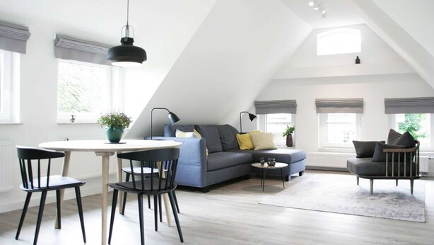 Ein modernes Loft mit Essbereich, Sofa und einem großen Fenster mit Blick.