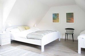 A modern bedroom with a white bed, a nightstand, a chair, and two abstract paintings on the wall. - Drunkenmannstieg 1, apartment 2 (Nieblum)