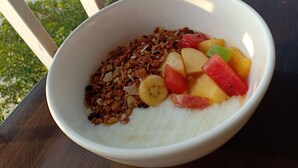 Un tazón de cereal con frutas y granola sobre una mesa.