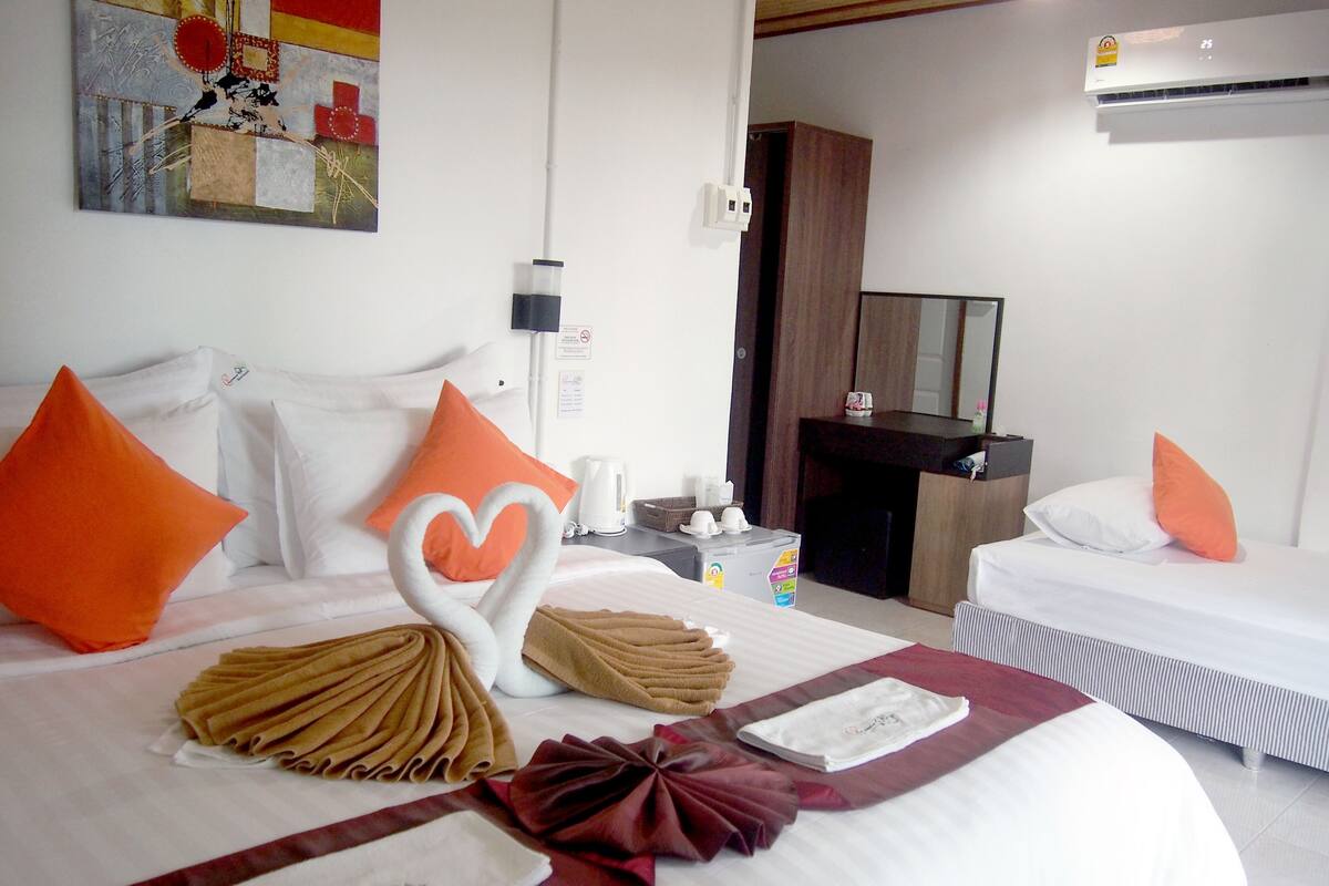 A hotel room with two beds, a coffee maker, a mirror, and a painting on the wall.