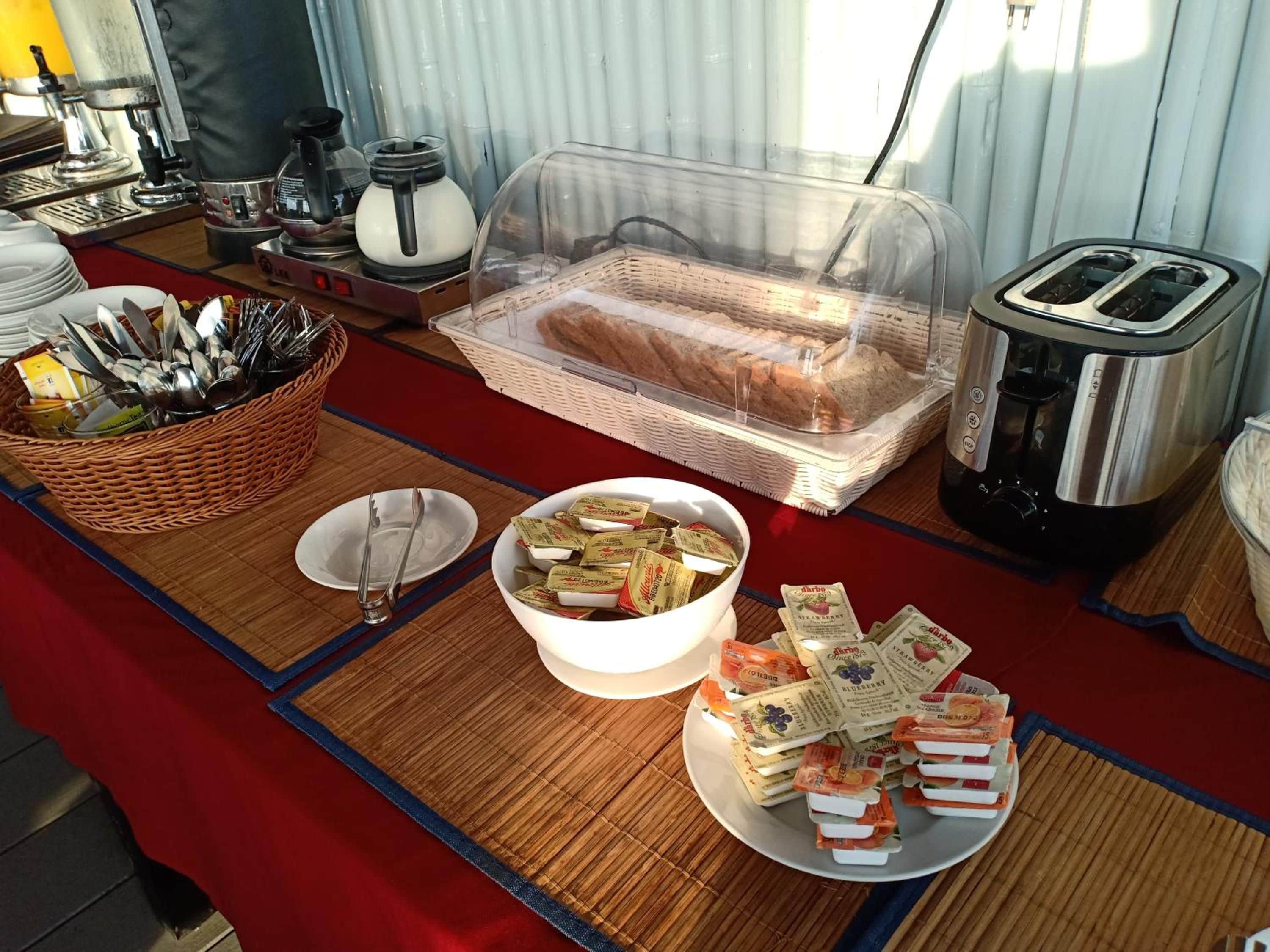 A breakfast buffet setup with bread, butter, and jam packets.