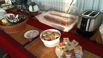 A breakfast buffet setup with bread, butter, and jam packets.