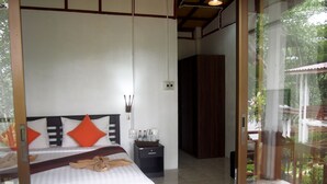 Un dormitorio con cama, almohadas, una mesita de noche y vistas a un balcón.