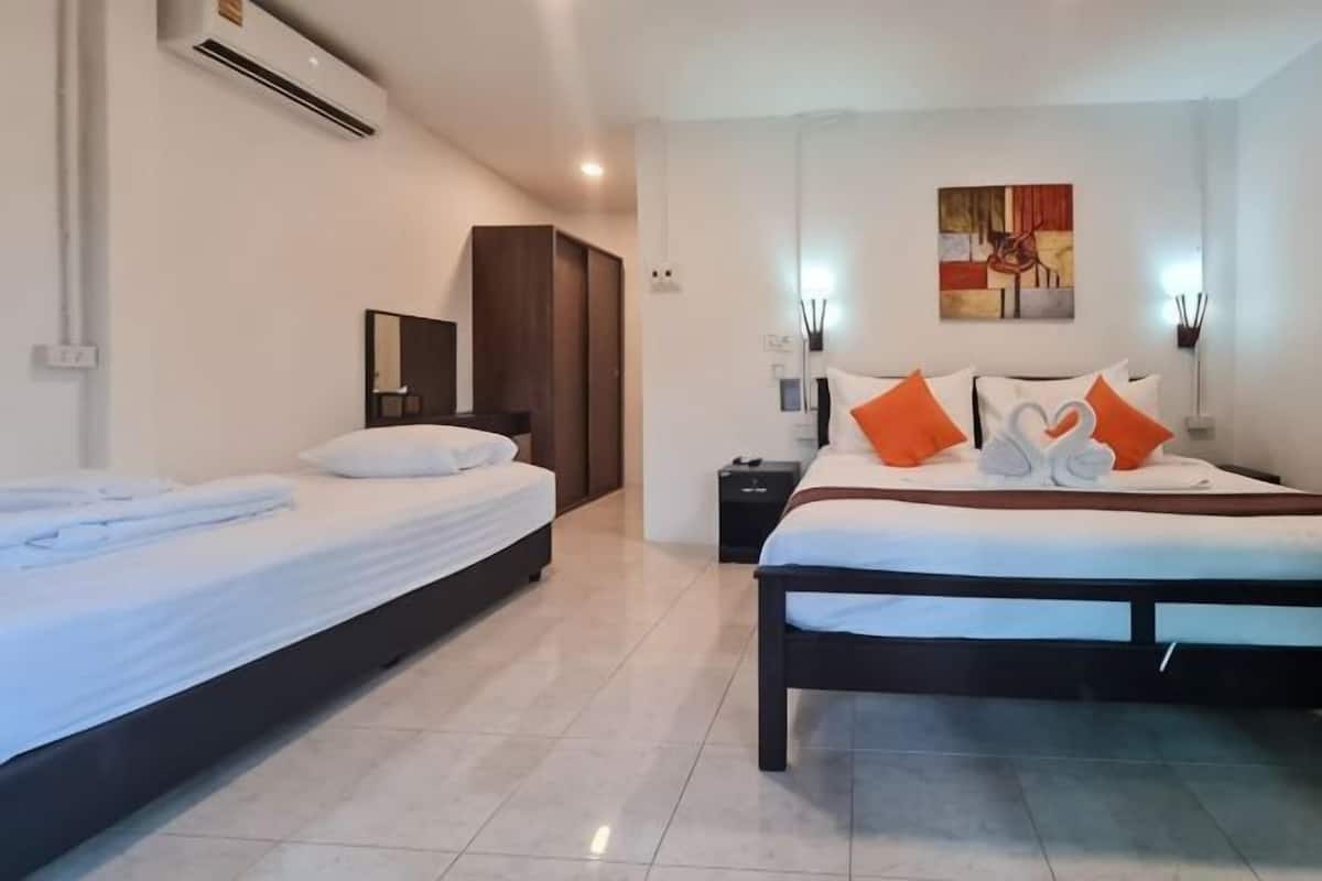 Une chambre dâhĂŽtel avec deux lits, une armoire, une table de chevet, une Ćuvre dâart accrochĂ©e au mur et un climatiseur fixĂ© au plafond.