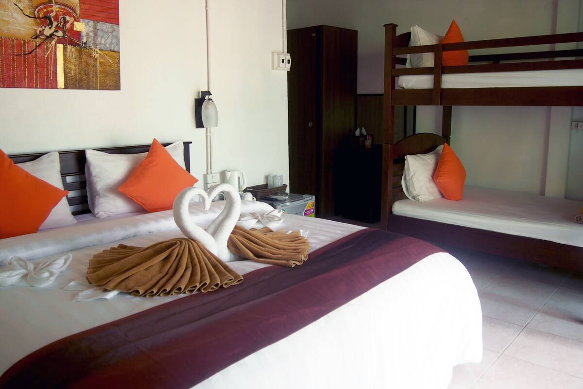 A hotel room with a bed, a bunk bed, and a painting on the wall.