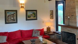 A cozy living room with a wooden ceiling, a fireplace, and a red sofa.