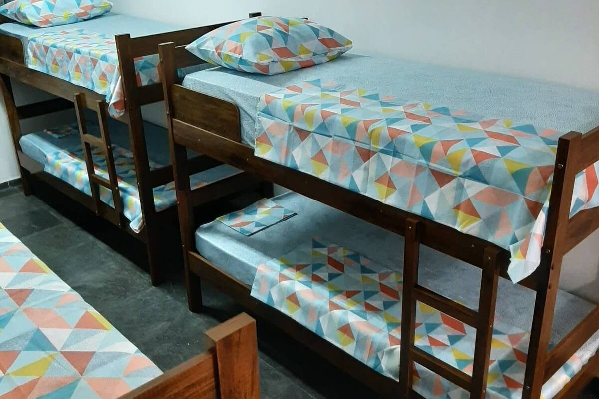 A dormitory room with bunk beds, wooden furniture, and a tiled floor.