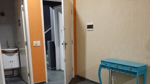 Una habitación con una mesa redonda, una consola azul y un vano que da a otra estancia.