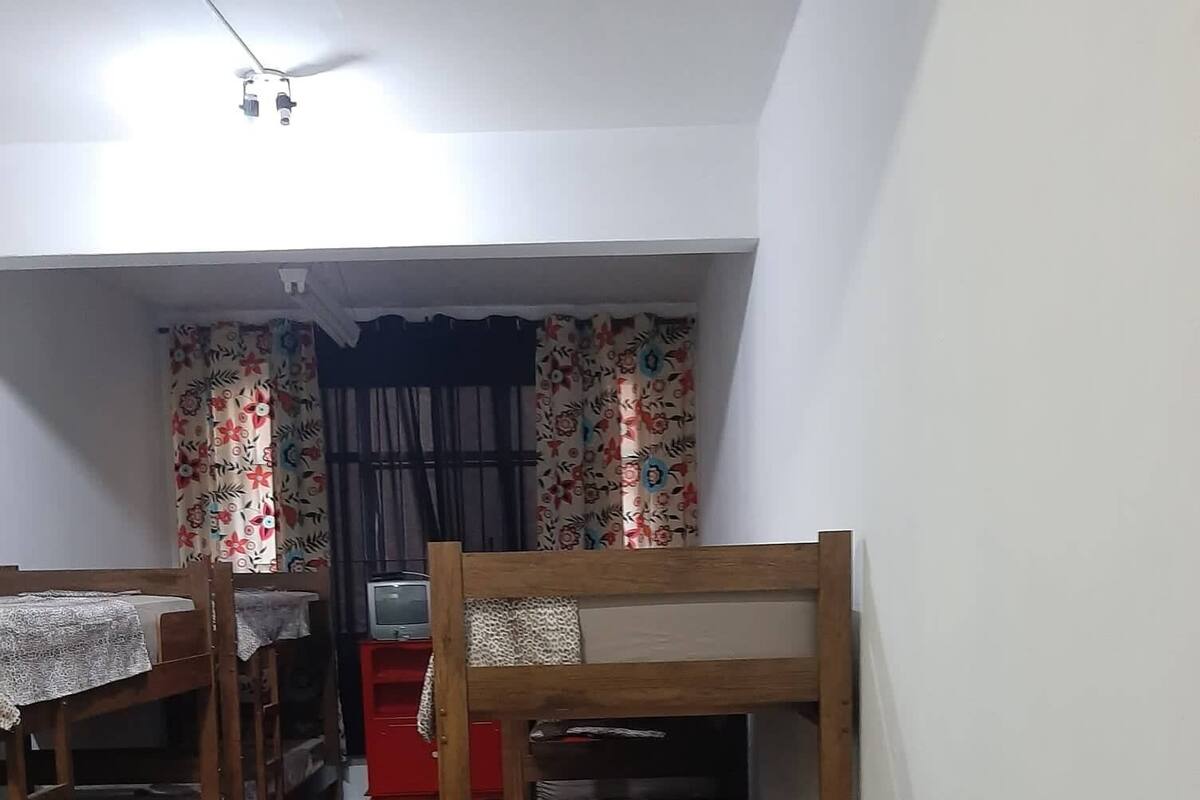 A dormitory room with bunk beds, a red cabinet, and a television.