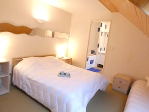 Ein Schlafzimmer mit einem großen Bett, Nachttischen, einem Spiegel und einer Tür zu einem Badezimmer.