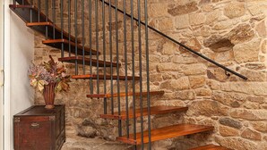 Una escalera de madera con barandillas de metal junto a un muro de piedra.