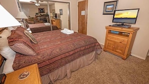 A bedroom with a large bed, a wooden dresser with a television, and a mirror reflecting the room. - 3407 Pine Hill 2 Bedroom Home by RedAwning (South Lake Tahoe)