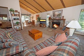 A cozy living room with a fireplace, a television, and a bookshelf. - 3407 Pine Hill 2 Bedroom Home by RedAwning (South Lake Tahoe)