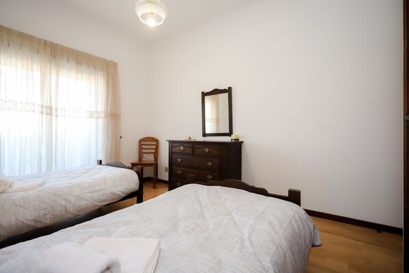 A hotel room with two beds, a dresser, a chair, and a mirror.