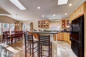 A spacious kitchen with a central island, wooden cabinets, and a black refrigerator.