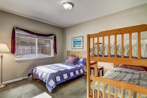 A bedroom with two beds, a window with curtains, a lamp, and a framed picture on the wall.