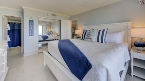 Un dormitorio con una cama grande, una mesita de noche, un espejo, un armario y un cartel colgado.