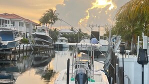 A marina with boats docked, a house with a red roof, and palm trees. - R & K’s Marathon Paradise 2/2 Duplex w/35` Dock & Cabana Club Included (Marathon)