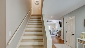 Eine Treppe führt zu einem Wohnbereich mit flacher Decke und einem an der Wand befestigten Fernseher.