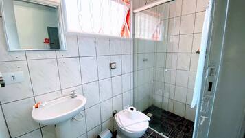 Un baño con lavamanos blanco, inodoro y cabina de ducha de vidrio.