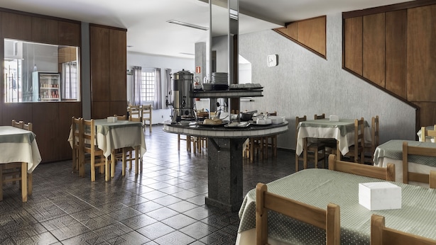 Un restaurante con varias mesas y sillas, una máquina de café y un amplio ventanal.