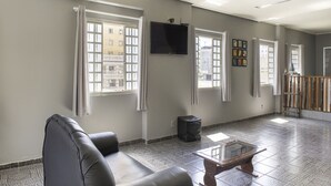 Amplia sala de estar con sofá de cuero, una mesa de centro de vidrio y un televisor montado en la pared.
