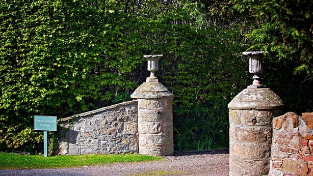 Un mur de pierre sur lequel est apposée une plaque indiquant : « Résidence du jardinier en chef. »