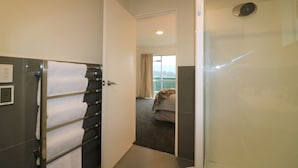 Ein Hotelzimmer mit Dusche, einem Bett mit Decke und Blick ins Freie durch das Fenster.