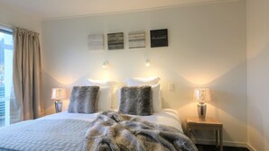Ein Hotelzimmer mit einem großen Bett, zwei Nachttischlampen, einem Fellüberwurf und drei an der Wand befestigten Schildern mit inspirierenden Zitaten.