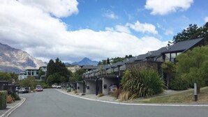 A residential street with houses, parked cars, and mountains in the background. - Spacious Lake View Alpine Townhouse Walk TO Town (Queenstown)
