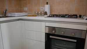 Una cocina con armarios blancos, estufa a gas y horno.