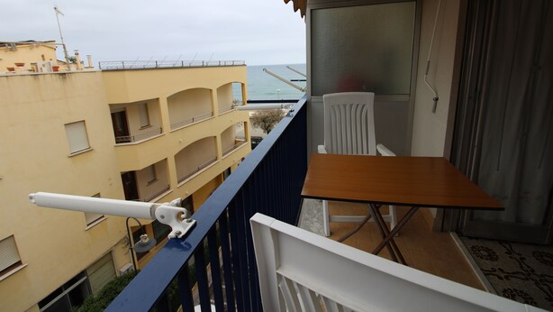 A balcony with a table and chair, overlooking a building and the sea. - Casa Lungomare (Cefalù)